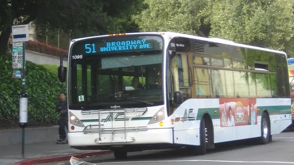 White bus pulling up to sidewalk bus station in Berkeley, California.