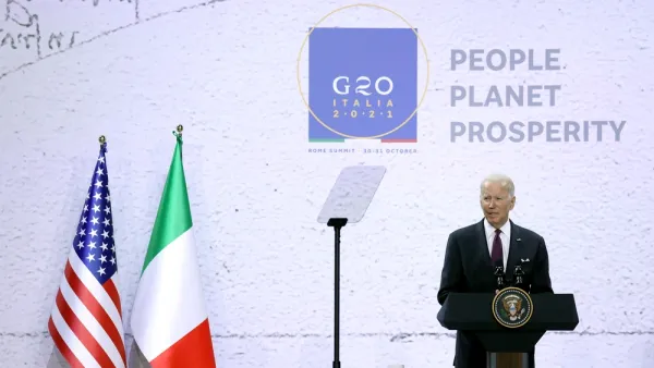President Joe Biden speaks at a podium in front of flags from the United States and Italy at the 2021 G20 conference in Rome, Italy.