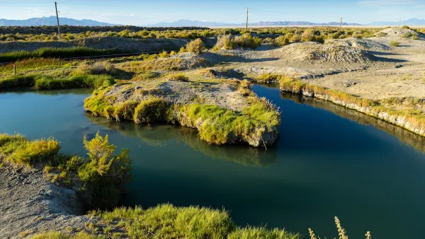 A hot springs in a low-lying desert area, with mountains in the distant background.