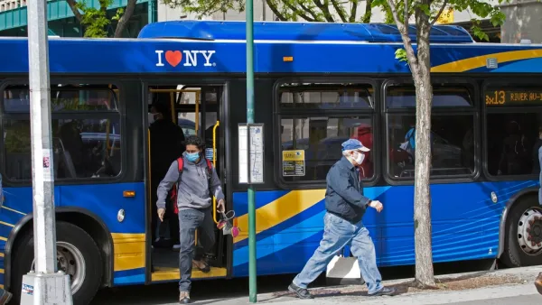 two riders wearing masks during the covid-19 pandemic exit a blue city bus in the Bronx in New York City.
