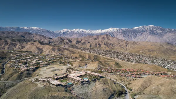 A large mansion is visible on a hill with the sprawling desert settlement of Rancho Mirage, California in the background.