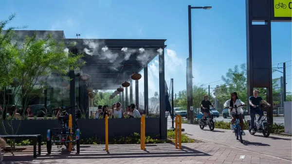 People ride bikes past outdoor restaurant patio with misters in Culdesac car-free development, Tempe, Arizona.