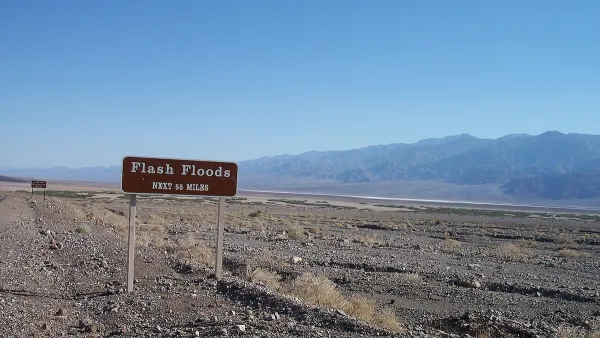 Brown and white "flash floods: next 55 miles" road sign in Death Valley, California