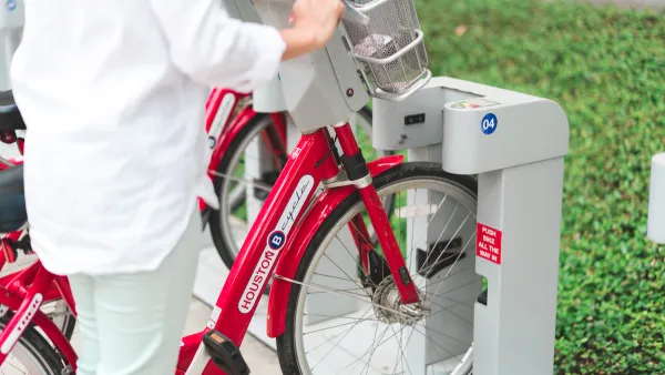 Close-up of person checking out bike at Houston BCycle station with red bikes