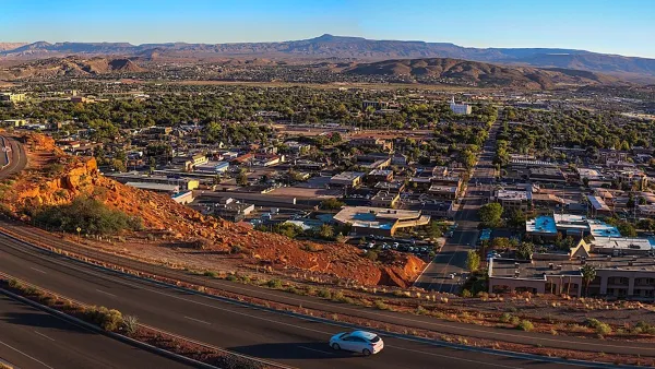 Aerial view of St. George, Utah at sunset with road in foreground and red mountains in background.