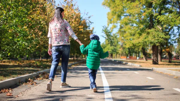 Parent and child walking, holding hands on mixed-use trail with trees