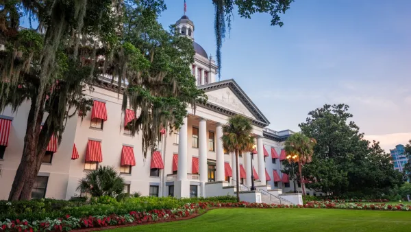 The buildings of the Florida State Capitol, old and new, are visible across a lawn in front of the old building.
