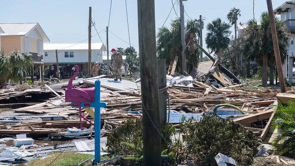 U.S. airmen in red berets and fatigues walk across rubble in Keaton Beach, Florida after Hurricane Helene heavily damaged the area.