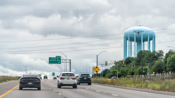 A view of a large water tower, with the words and logo of Fort Worth, looming over a wide freeway.