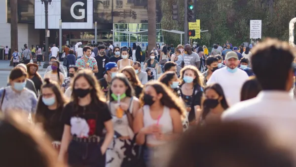 Large numbers of young people, some wearing and masks and others note, walk around an outdoor shopping mall in Southern California.