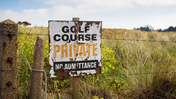 A derelict sign on a barbed wire fence reads “Golf Course, Private, No Admittance.”