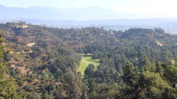 The fairway of a golf course is visible amidst the rolling hills of Griffith Park above Los Angeles.