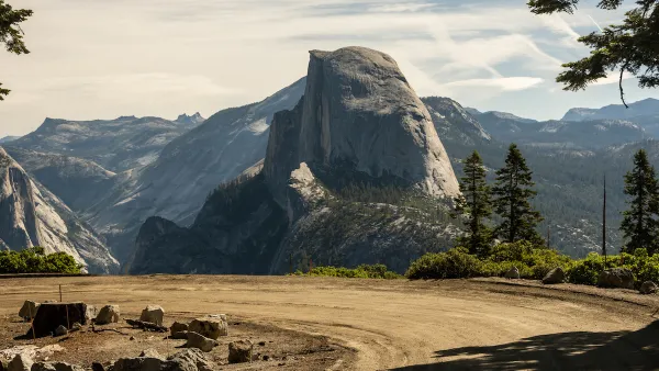 A dirt road turns int he foreground while Half Dome looms majestically in the background.