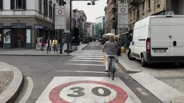 A bike rider navigates a bike lane in a traffic limited zone in Italy, where only one delivery van is visible on the street.