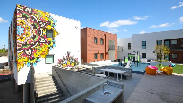 The interior of a multi-story apartment building includes a children's' playground and a colorful mural.