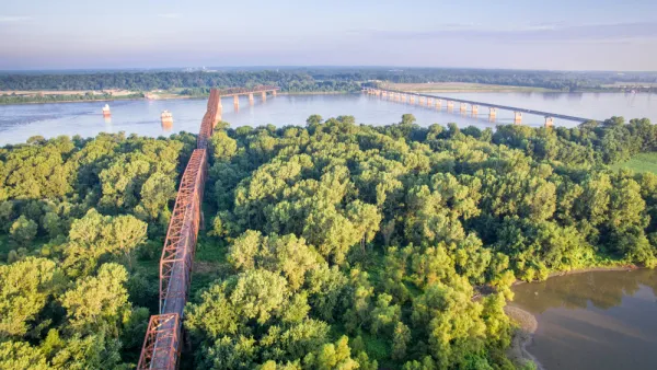 Two bridges cross the Mississippi Rivera midst thick vegetation and few other signs of human intervention.