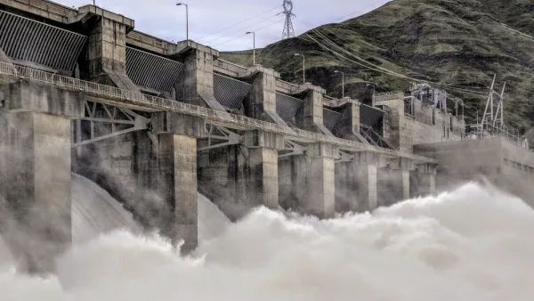 Water rushes over a spillway at a large concrete dam.
