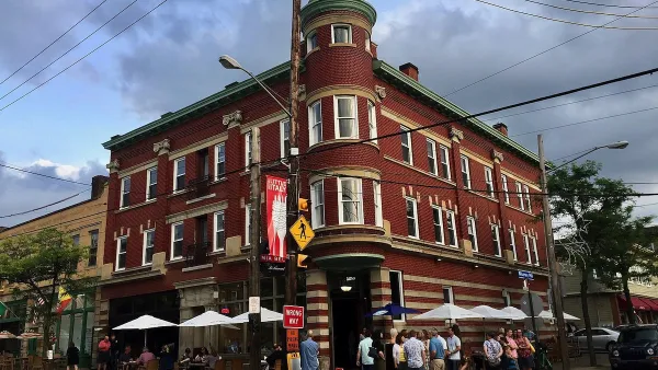 Brick three-story building with restaurant patio umbrellas outside ground floor in Little Italy neighborhood in Cleveland, Ohio.
