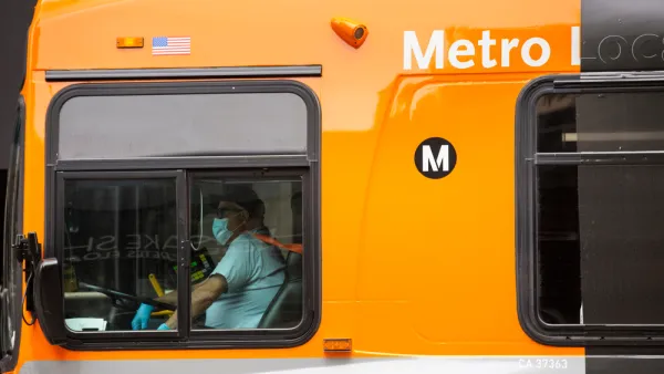 A Metro Los Angeles bus driver is behind the wheel while wearing a mask.