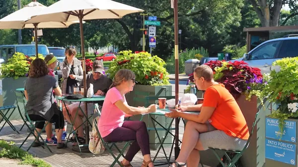 People sitting at small tables in a public parklet in Minneapolis, Minnesota.