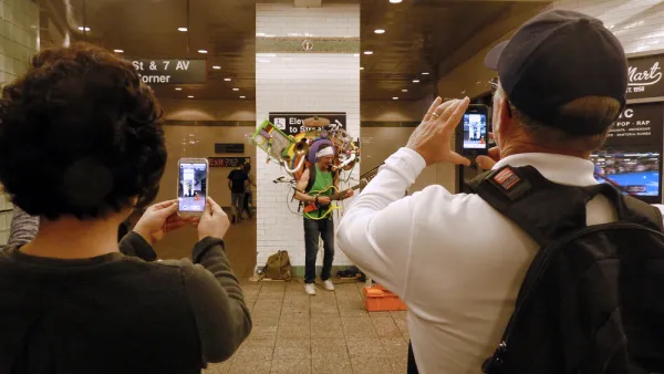 A performer holding numerous instruments plays for a crowd in the New York Subway.
