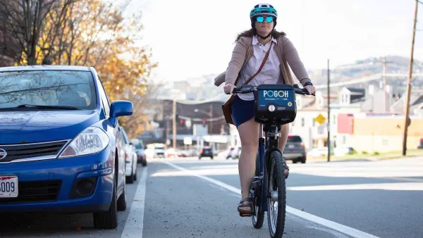 Woman wearing helmet riding POGOH bike share bike in bike lane in Pittsburgh, PA.