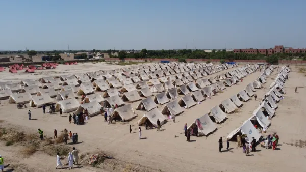 A humanitarian facility, with rows of tents, is set up in a dusty field in Pakistan.