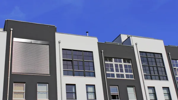 The top floors of a row of pre-fab apartments or condos are shown against a blue sky.