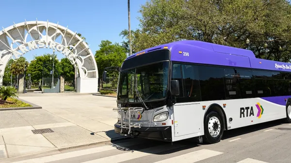 White and purple RTA bus inf ront of white archway to Armstrong transit station in New Orleans, Louisiana.