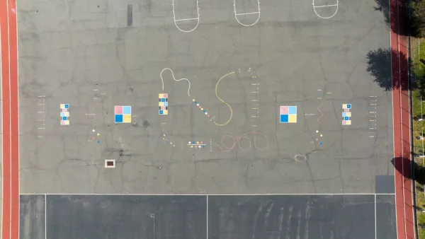 A school blacktop is viewed from bird’s eye view. The blacktop is adorned with painting and colors for games. but no children are present.