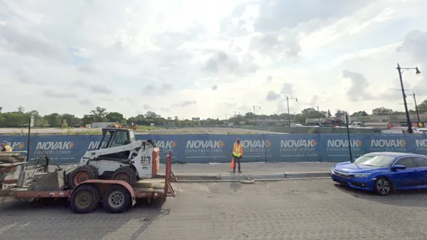 Google Street View of empty construction site with blue construction fence