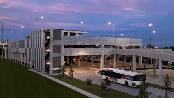 View of Westpark/Lower Uptown transit center in Houston with bus exiting three-story garage vuilding and purple sunset sky in background