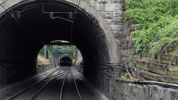 View into gray stone train tunnel with visible opening on other side