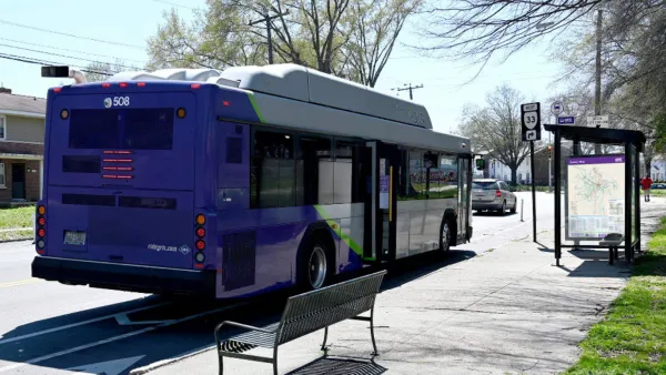 Purple GRTC bus stopped at a bus station with bench and shelter in Richmond, Virginia.