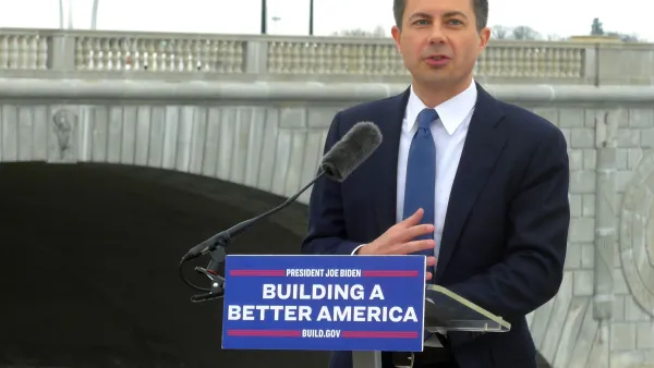 U.S> Department of Transportation Secretary Pete Buttigieg delivers a speech in front of a bridge in Washington, D.C. The podium where he stands has a sign that reads: "Building a Better America."