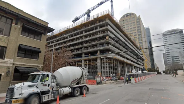 Construction on a high-rise, with cement trucks and tall cranes, is visible on an Austin Street.