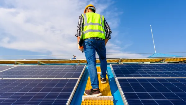 Worker standing between solar panels on roof
