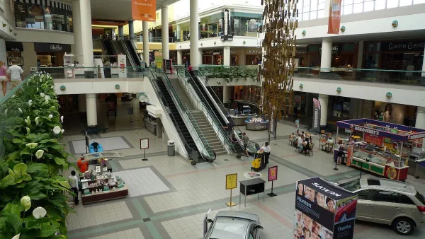 View form second story inside Southdale Mall in Edina, Minnesota with escalators and model cars parked on downstairs floor.