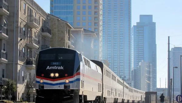 Texas Eagle Amtrak train pulling into station in Austin, Texas with glass high-rise buildings in background.