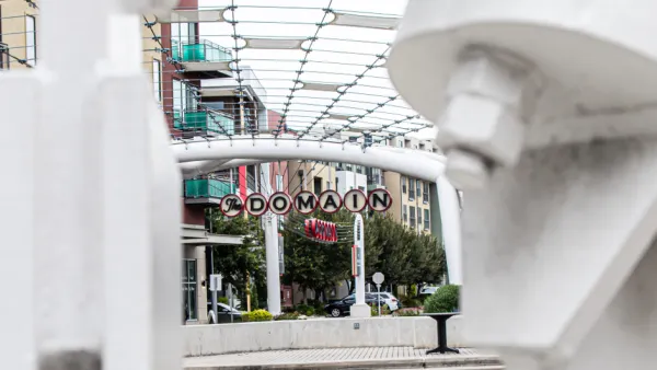 A picture of a decorative sign announcing “The Domain” surrounded by high density shops and apartments.