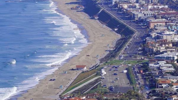 A parking lots and homes sit on a bluff above a large beach on Pacific coast in Southern California.