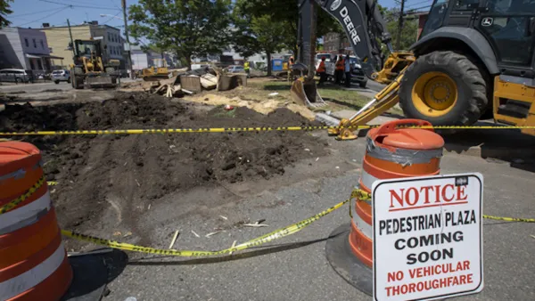 Pedestrian plaza construction site with orange cones and excavator in Jersey City, New Jersey.