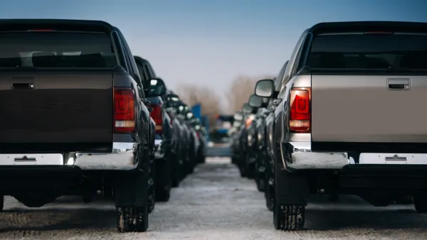 Large pickup trucks are parked in neat rows extending into the fuzzy background of the image.