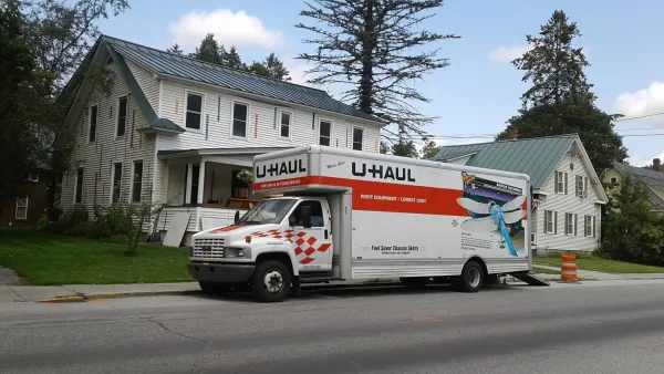 U-Haul moving truck in front of white house and trees