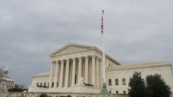 The exterior of the U.S. Supreme Court, with an American flag flying above its large columns and white marble exterior.