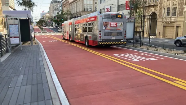 Red bus only lanes on Van Ness Avenue in San Francisco, California with bus stopped at station.