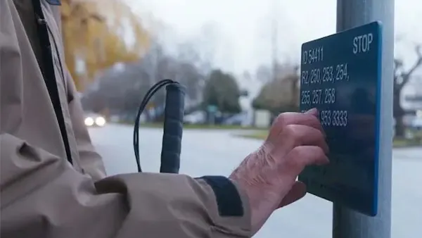 Close-up of hand reading Braille sign at bus stop in Vancouver, British Columbia.