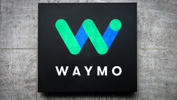 Blue and green Waymo logo on black square mounted on grey concrete background