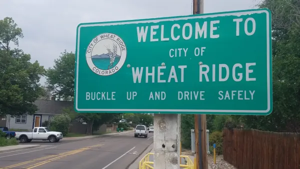 A road sign reads "Welcome to City of Wheat Ridge Buckle Up and Drive Safely"