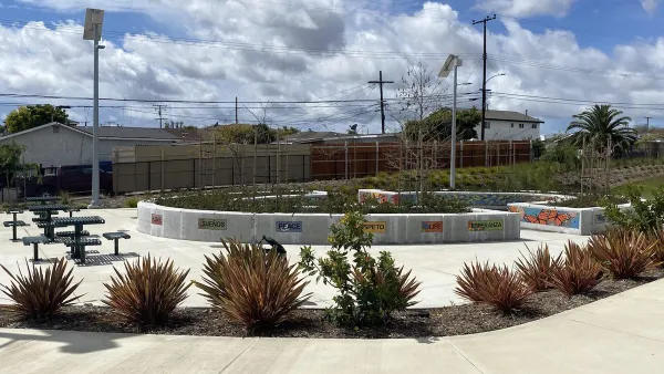 Concrete walkway with landscaping, decorative tiles, and picnic tables in a Los Angeles County park.